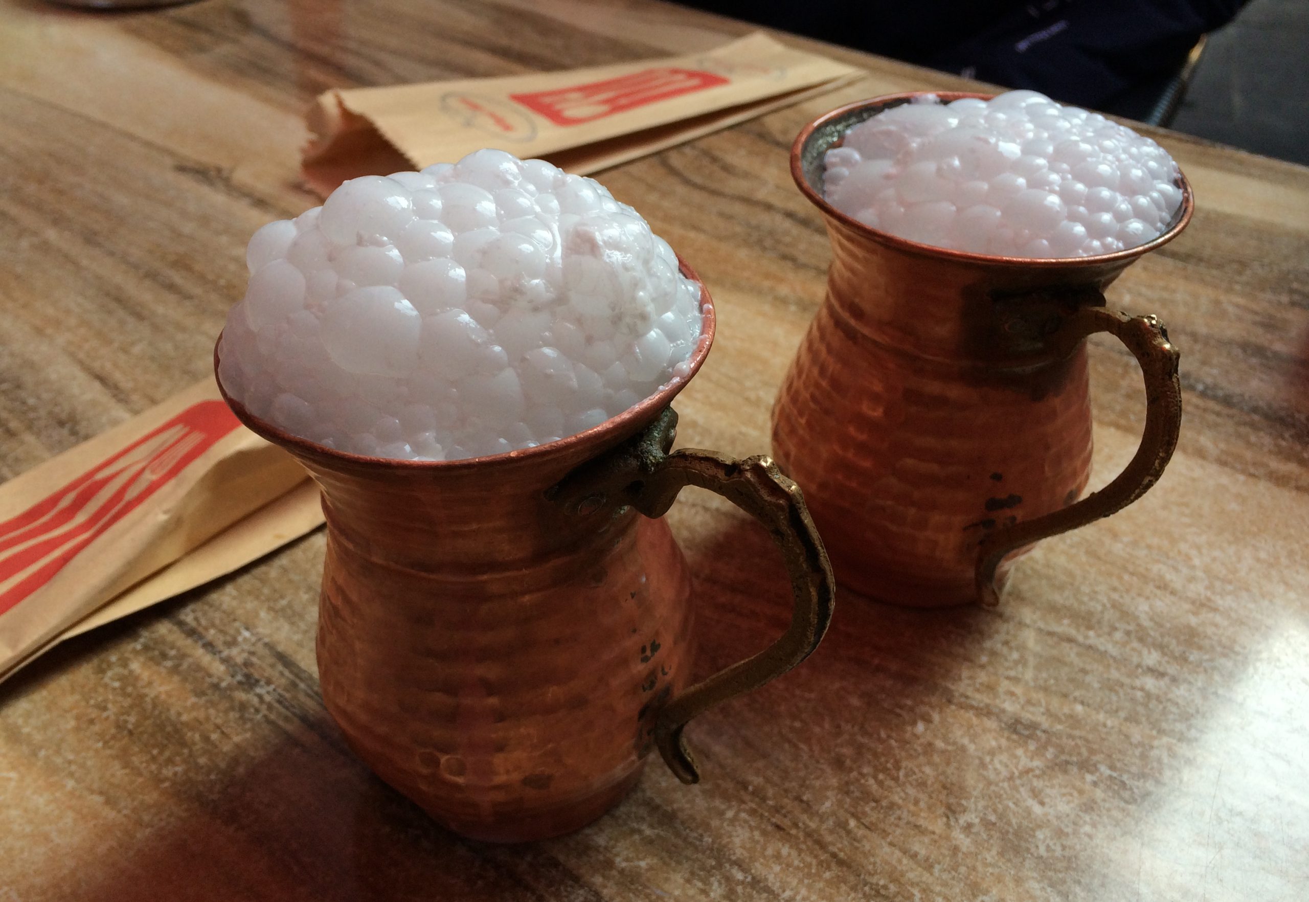 Cold frothy Turkish ayran yogurt drink served in a traditional copper cup