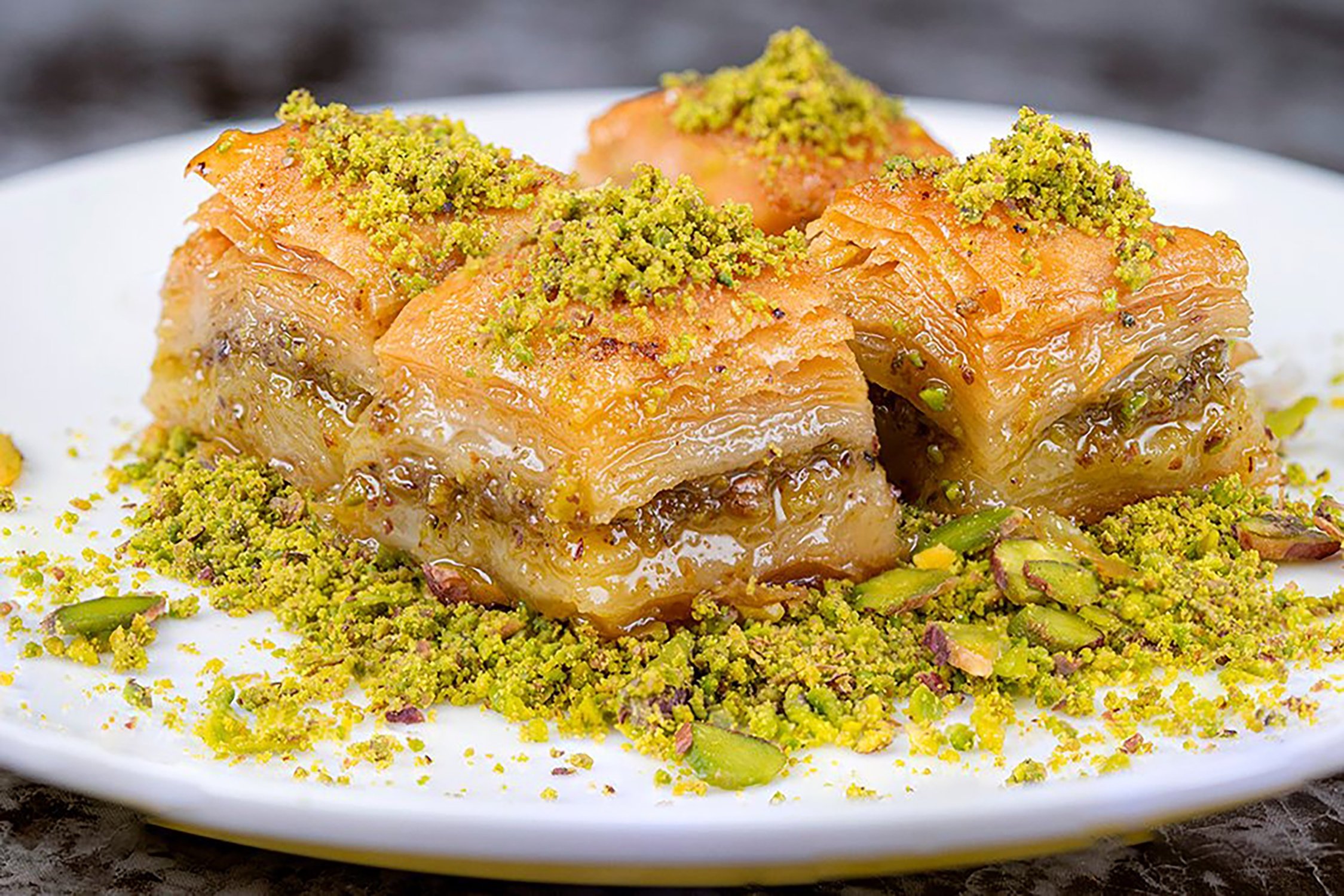 Tray of Gaziantep baklava with crushed green pistachios over golden filo pastry