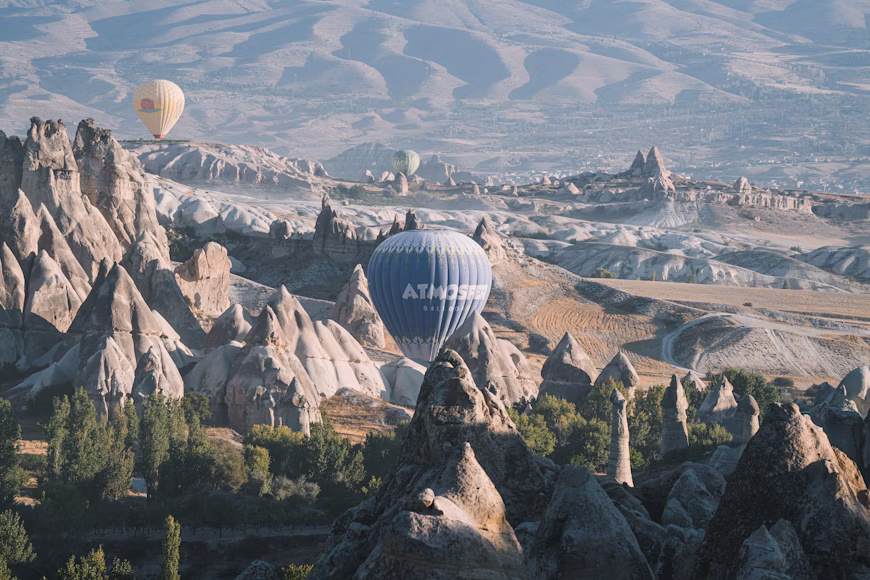 Hot air balloons rising above Cappadocia’s fairy chimneys and rock formations at sunrise