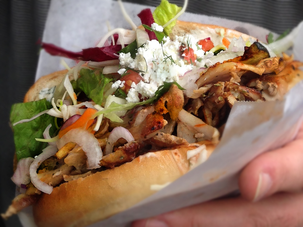 Turkish döner kebab meat slow-roasting on a vertical rotisserie being sliced thin