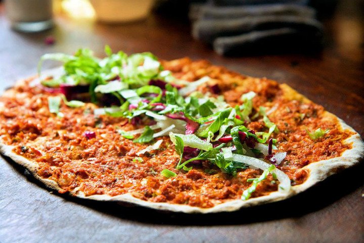 Lahmacun thin flatbread topped with minced lamb, tomatoes, parsley, and lemon