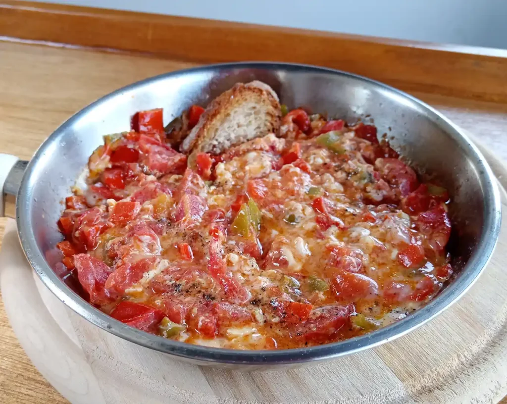 Menemen scrambled eggs cooked with tomatoes and green peppers in a copper pan