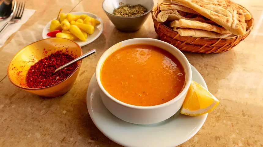 Bowl of Turkish mercimek çorbası red lentil soup with lemon wedge and dried mint