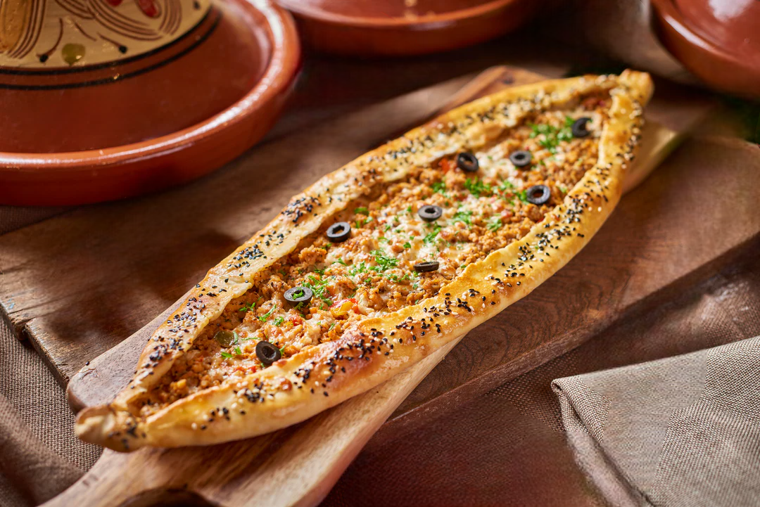 Boat-shaped Turkish pide flatbread topped with melted cheese and minced meat