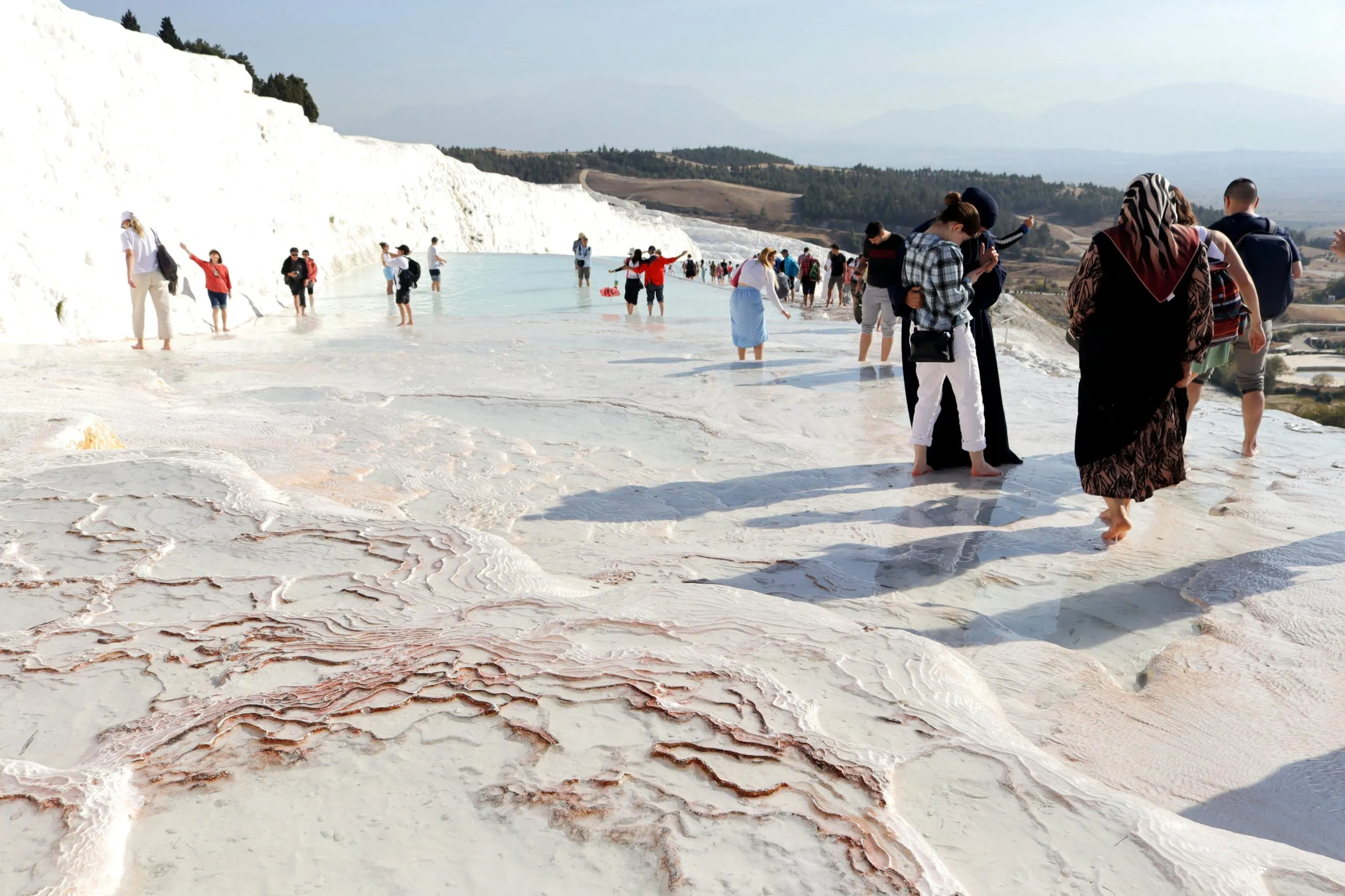 Walking the White Terraces Pamukkale Turkey Tourists walking barefoot on Pamukkale white travertine terraces Turkey