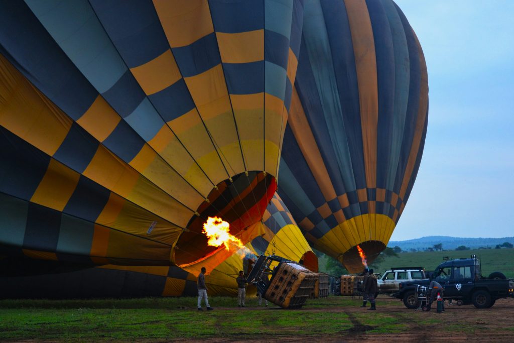 Crew inflating a hot air balloon at sunrise on a Cappadocia launch field with multiple balloons preparing