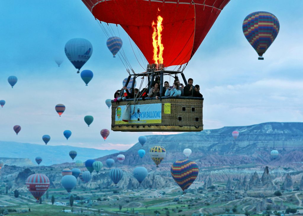Passenger view from a Cappadocia hot air balloon basket looking down at fairy chimneys and valleys at sunrise