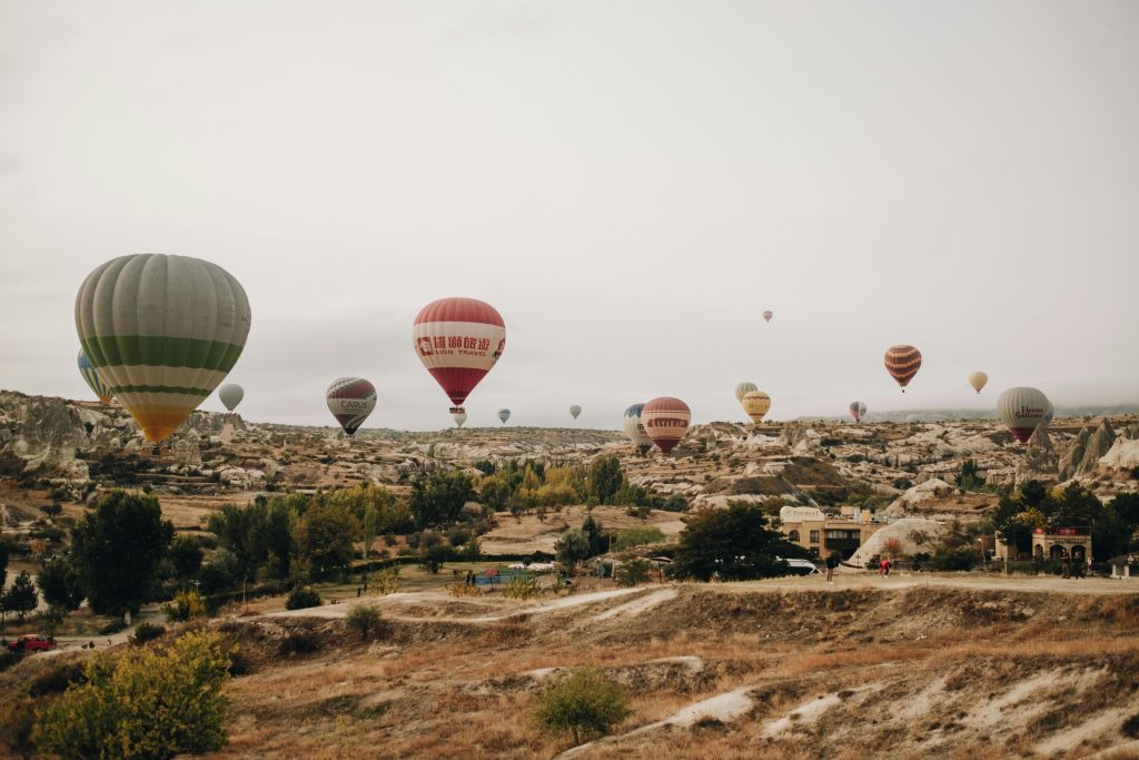 Cappadocia hot air balloons drifting in autumn light over Rose Valley with golden hues on the rock formations