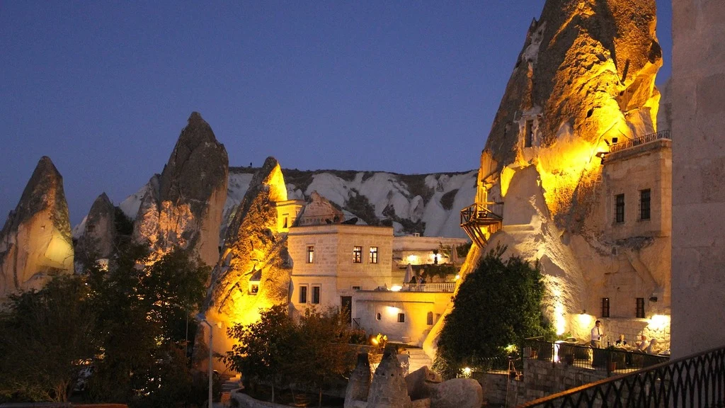 Cappadocia cave hotel rooftop terrace with hot air balloons rising in the morning sky over Göreme